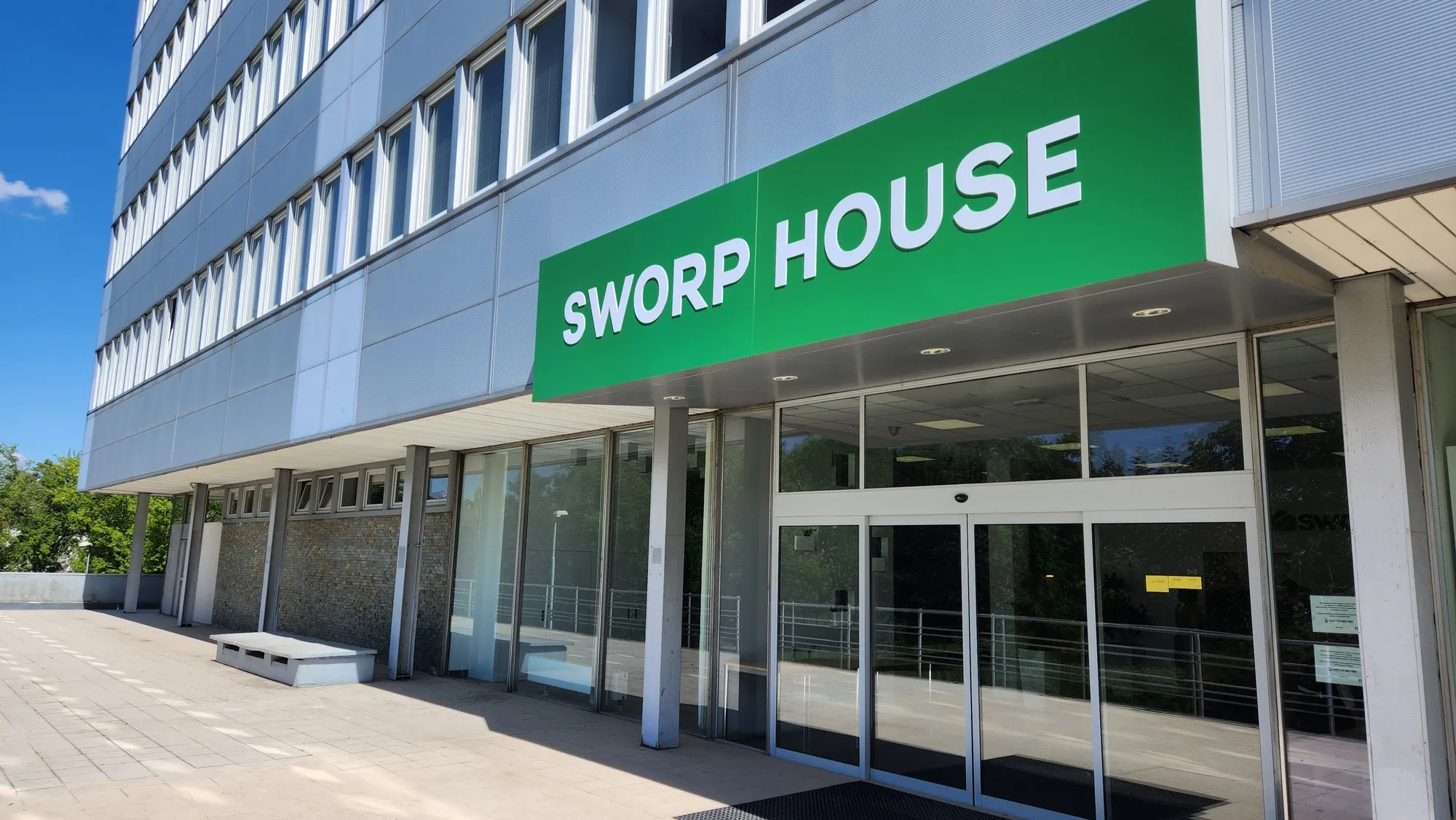 Entrance to Sworp House with glass automatic sliding doors under a green sign.